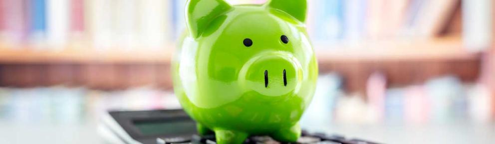 Green piggy bank sitting on a calculator