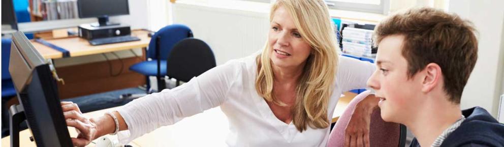 Young person with older careers advisor looking at a screen in a library.