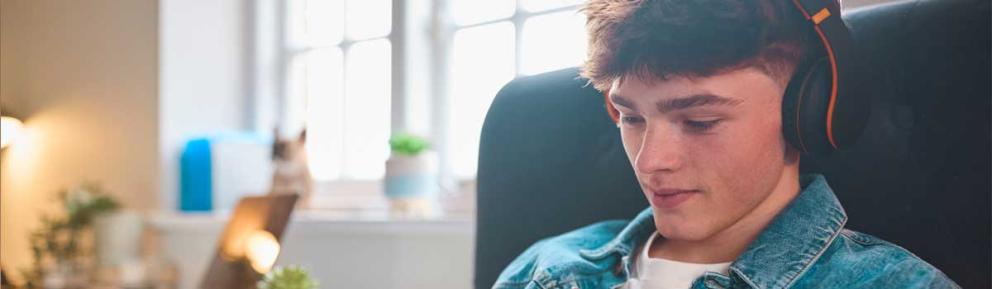 Young person wearing over-ear headphones sitting on a sofa
