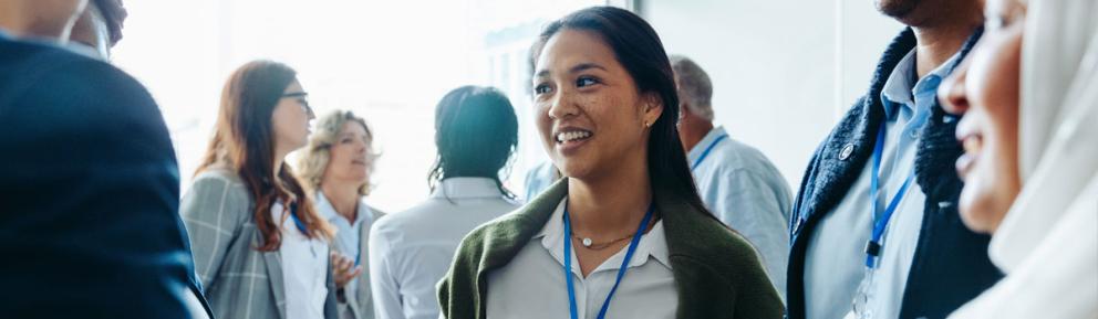 Woman with lanyard at a professional event talking with a group of people