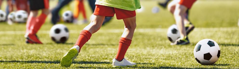 Children play football on a green field.