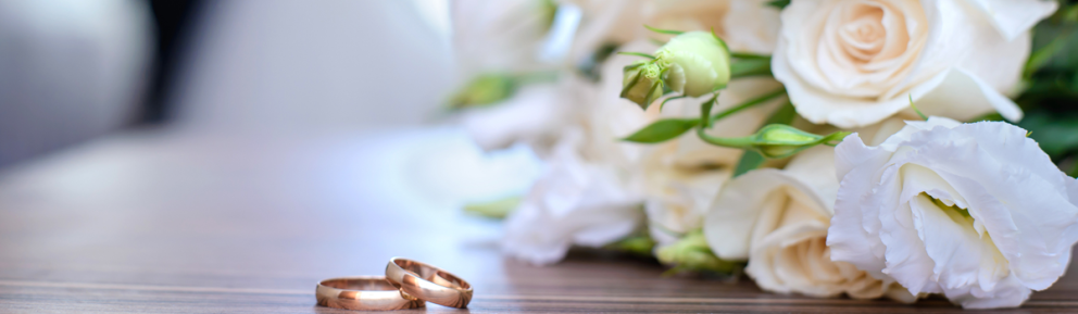 wedding rings on a table with a bouquet of white flowers