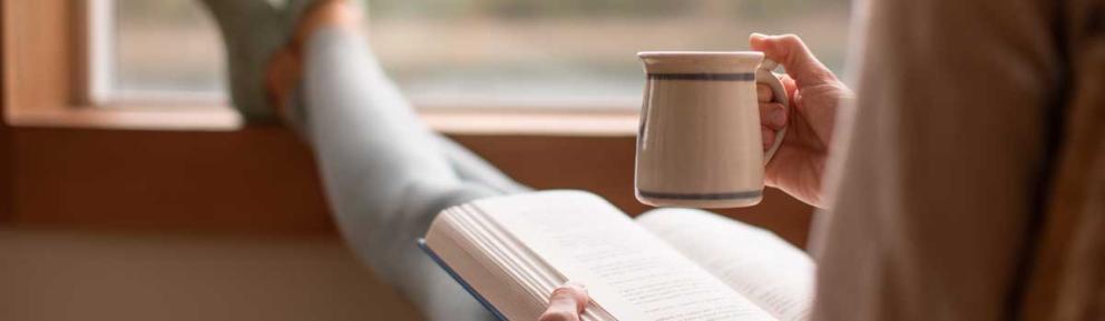 Person relaxing with a book and a hot drink