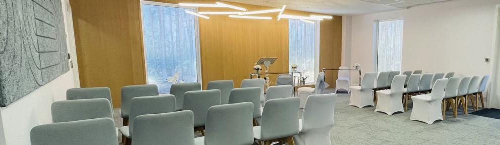 Carpeted room for ceremonies with covered chairs and modern lighting