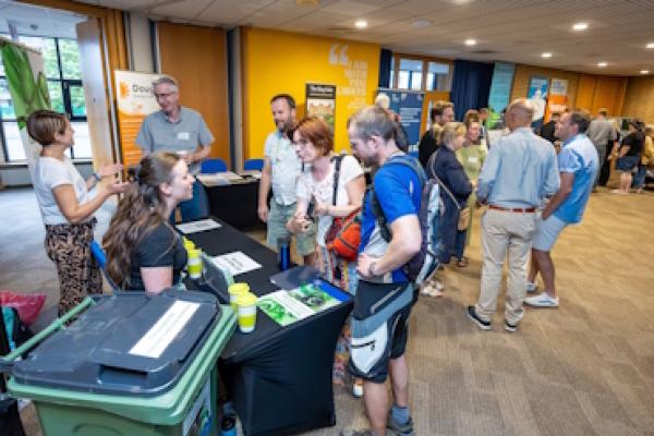 Several people gather around a stall about glass recycling at the Bracknell Forest Climate Summit 2025.