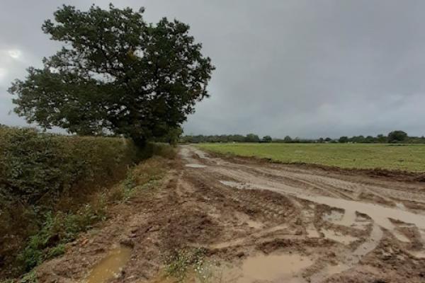 The "before" image of the western diversion track. The road is very muddy with several puddles and tyre marks.