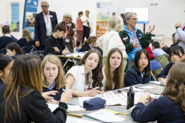 A group of students at the Secondary School climate conference sitting around a table making notes on large pieces of paper.