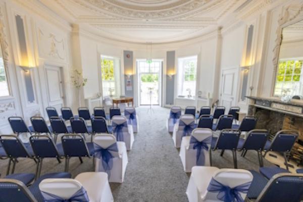 A back view of the Haversham Room at South Hill Park, with rows of chairs facing a bright doorway.