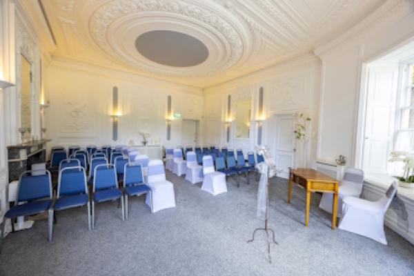 The front side view of the Haversham Room. There are rows of chairs facing forwards and a table and two chairs at the front.