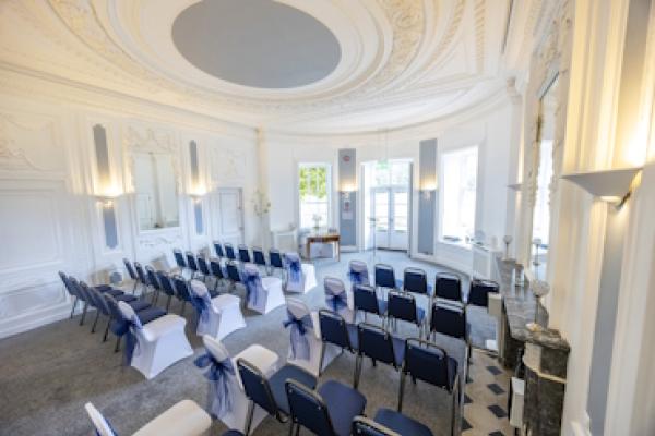 The Haversham Room from the back, showing the tall, decorated ceiling and rows of chairs.