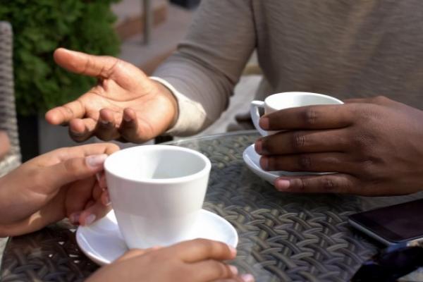 Two people chatting over cups of tea or coffee