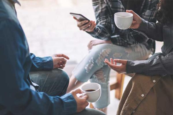 People talking in a group with coffee cups and phones