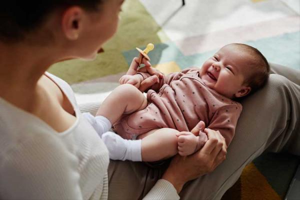 baby on a woman's lap, smiling up at her