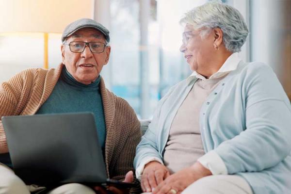 Elderly man and woman relax on the sofa with a laptop