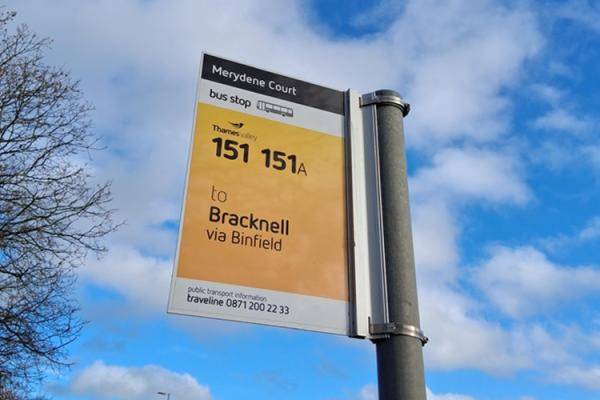 Bus stop sign for routes 151 and 151A to Bracknell via Binfield at Merydene Court, against a blue sky.