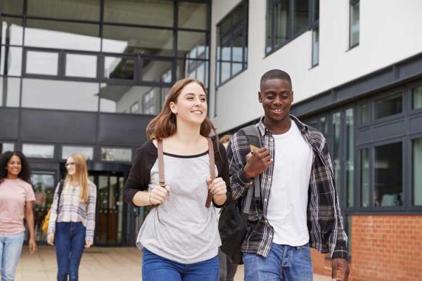 Young people with backpacks walking out of a college.