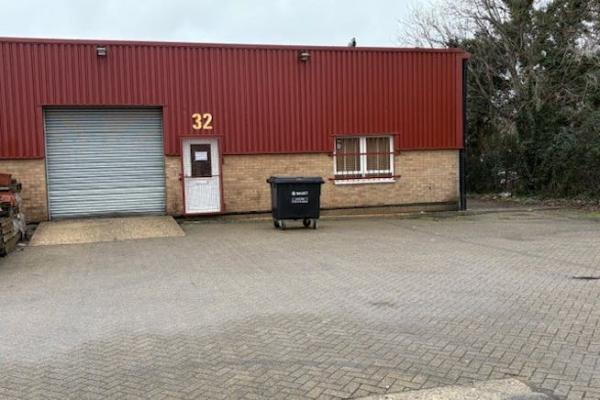 Front of business unit with the number 32 over the door and a big black bin outside