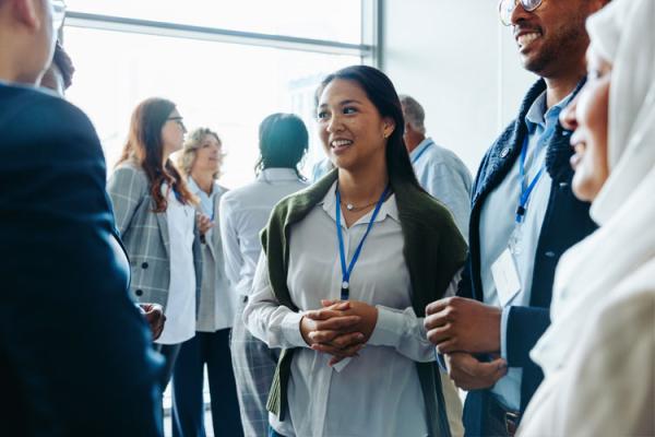 Woman with lanyard at a professional event talking with a group of people