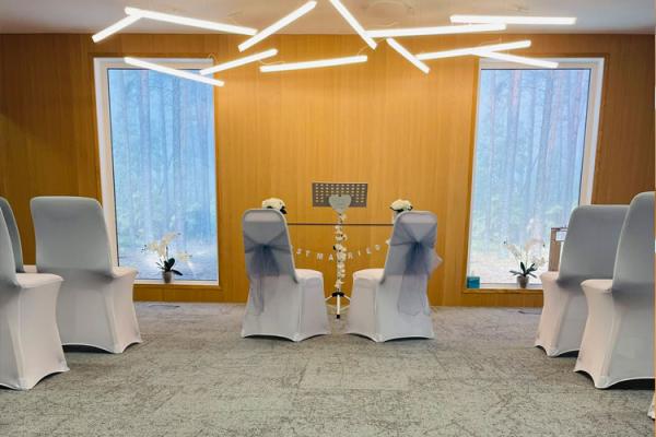 Carpeted room for ceremonies with covered chairs and modern lighting