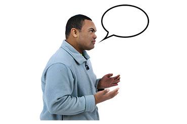 A man in a grey pullover with a speech bubble above his head, gesturing with his hands.