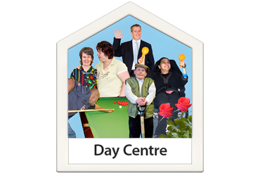 People engaging in activities at a day centre, including playing pool and interacting with each other.