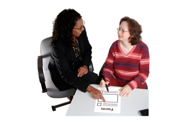 A professional woman helping another woman fill out a form